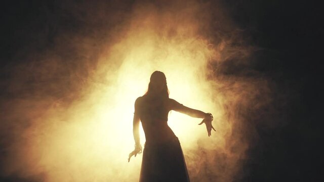 Woman dancing in smoke on a dark background