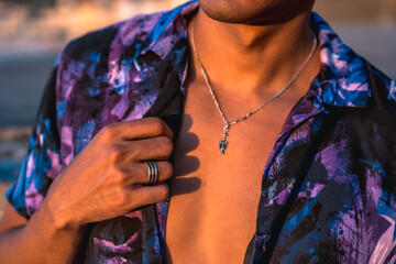 Fototapeta premium Summer lifestyle, a young Latino enjoying summer vacations. with purple flower shirt and sunglasses, hand detail