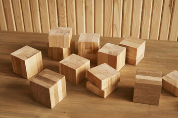 wooden cubes of different sizes lie on the table against the background of a wooden wall