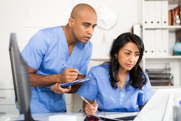 Obraz premium Two focused doctors working with patient records on laptop in modern medical office