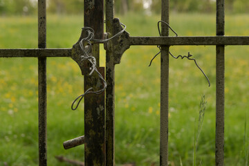 Fragment of an iron gate closed with an iron wire instead of a lock