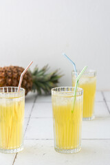 Delicious sweet refreshing pineapple juice with ice in glasses with a straw