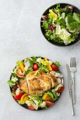 Delicious hearty lunch, chicken breast baked with spices and a mix of salad with tomatoes, radishes and cauliflower, top view, copy space