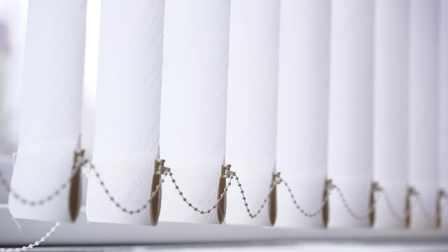Close view of white opened vertical paper modern roller blinds swaying with light wind