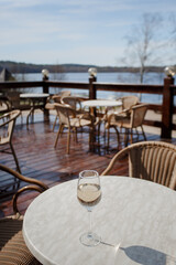 A glass of white wine on a white table on the terrace. Glare from a glass of wine and sunbeams