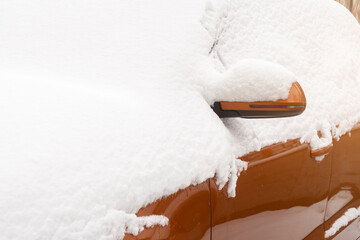 Orange car covered with fresh white snow. View after snowfall in winter season. Mirrow and side are partially visible. - Powered by Adobe