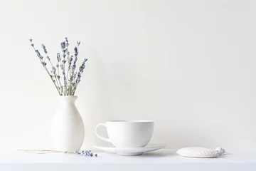 Poster Still life with minimal composition, lavender dried bouquet, ceramic white cup and hot beverage tea or coffee, morning mood in beige tone © Savvapanf Photo ©