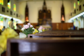 rose flowers at corner of bench in church as decoration for wedding ceremony