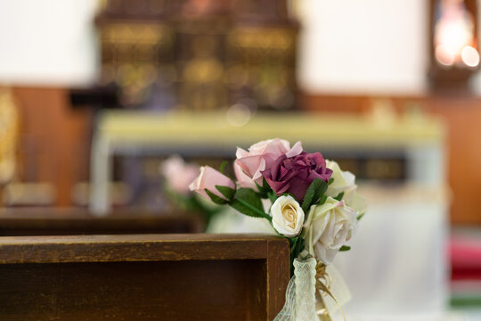 rose flowers at corner of bench in church as decoration for wedding ceremony