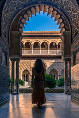 Silhouette of a woman in a dress walking peacefully through the Real Alcazar in Seville, Spain