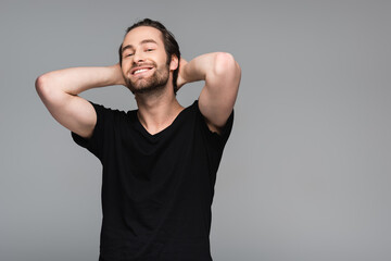 joyful bearded man in black t-shirt posing isolated on grey.