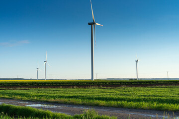 Fototapeta na wymiar Turbines generate renewable green energy in windmill farm in countryside