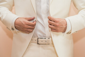 Closeup shot of a man buttoning his white suit