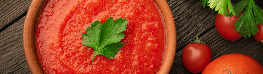 Top view bowl of tomato soup and fresh tomatoes on wooden background panoramic banner