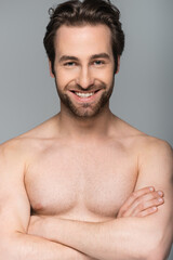 Naklejka premium smiling shirtless man posing and looking at camera isolated on grey.
