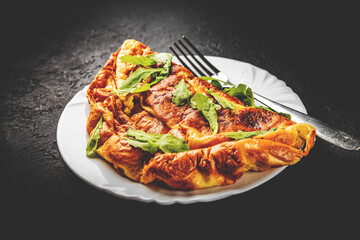 omelet in white plate on Dark grey black slate background