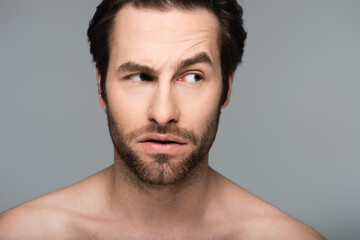 curious and good-looking man looking away isolated on grey.