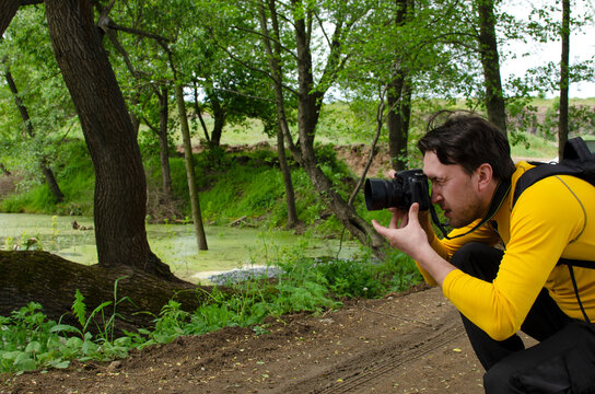 Photographer taking pictures of the river in the forest with a digital camera