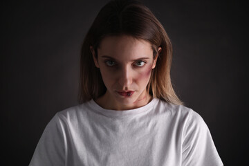 Woman with facial injuries on black background. Domestic violence victim