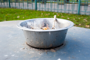 metal ashtray with cigarettes in a public place