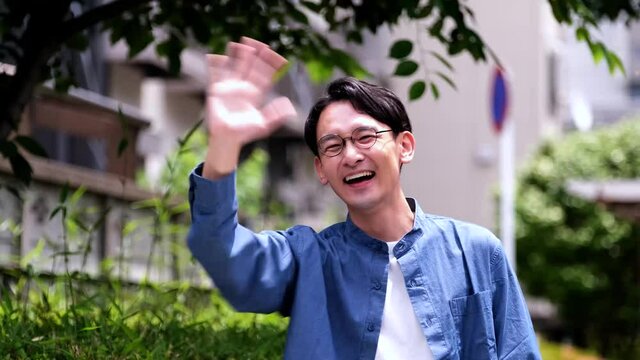 待ち合わせ相手を見つけて手を振る男性