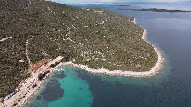 Coastline of Uvala Mrtvaska, clear Adriatic Sea and lush forest. Aerial pullback