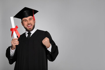 Emotional student with graduation hat and diploma on grey background. Space for text