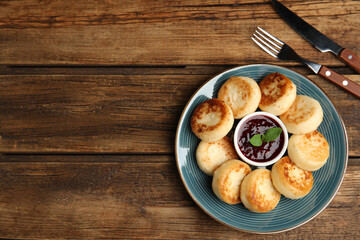 Delicious cottage cheese pancakes with jam and mint on wooden table, flat lay. Space for text