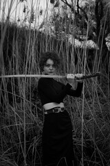 Curly-haired girl with a sword in the forest