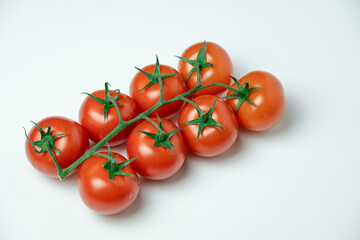 Red tomatoes on branch on a white background