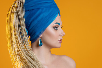 Young charming blonde in a blue turban and micro-dreadlocks, toning eyebrows,