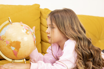 Cute little schoolgirl looking at the globe and learning - children's education concept