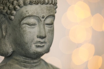 Buddha statue against blurred lights, closeup. Space for text