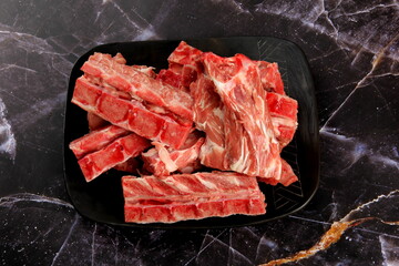Raw meat with bone on clay plate and luxury marble background. Raw meat with beef bone. Bone selection for soup. Raw meat with bone close-up