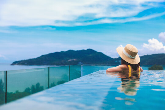 Asian travel bikini woman relax in infinity pool resort on phuket beach Thailand