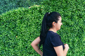 Naklejka na ściany i meble Hispanic Woman runner listening to music while jogging.