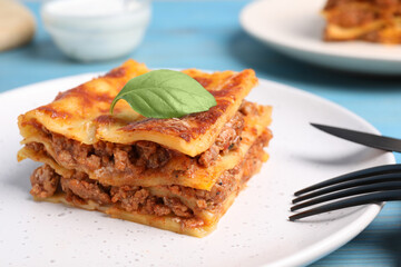 Tasty cooked lasagna served on light blue table, closeup