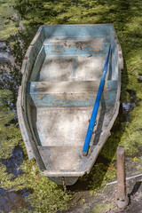 Old abandoned iron boat near a duckweed pond in the daytime