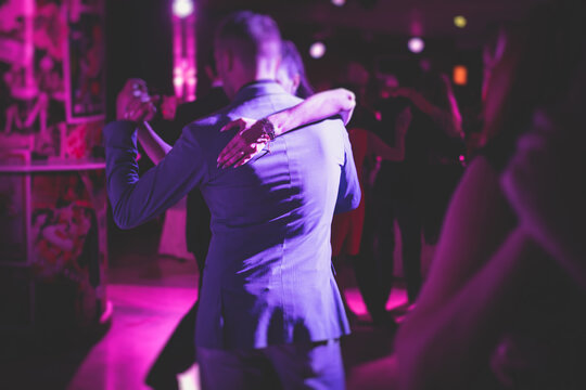Couples dancing traditional latin argentinian dance milonga in the ballroom, tango salsa bachata kizomba lesson in the red, purple and violet lights, dance festival