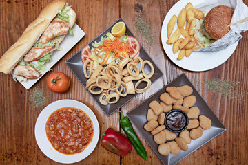 Top view image of nuggets, roman calamari tapa, meat in sauce, chicken sandwich and hamburger