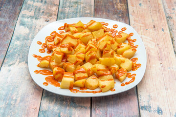The best known of the typical Madrid tapas, patatas bravas on a white plate