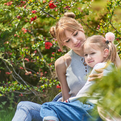 Beautiful blonde mother and child daughter together in a Blossom park