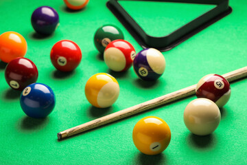 Many colorful billiard balls and cue on green table