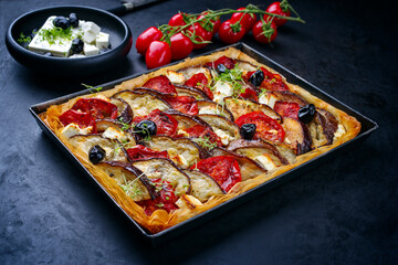 Traditioneller französischer Tart mit Auberginen, Tomaten und Feta Käse serviert als close-up in einer Backform 