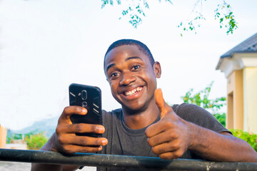 Excited african american millennial Young man hold smartphone feel euphoric reading good news,...