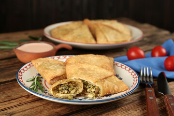 Delicious samosas with sauce served on wooden table, closeup