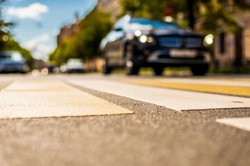 Clear day in the big city, the car goes down the street. View from the pedestrian crossing