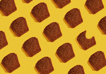 Dark rye bread pieces pattern on a yellow background. Food pattern.