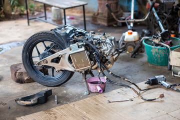 Motorbike In the shop, the motorbike is being disassembled, draining the automatic motorbike oil. Change the oil in a small tank, support the old oil under the car, repair a motorcycle 