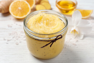 Body scrub in glass jar on white wooden table, closeup
